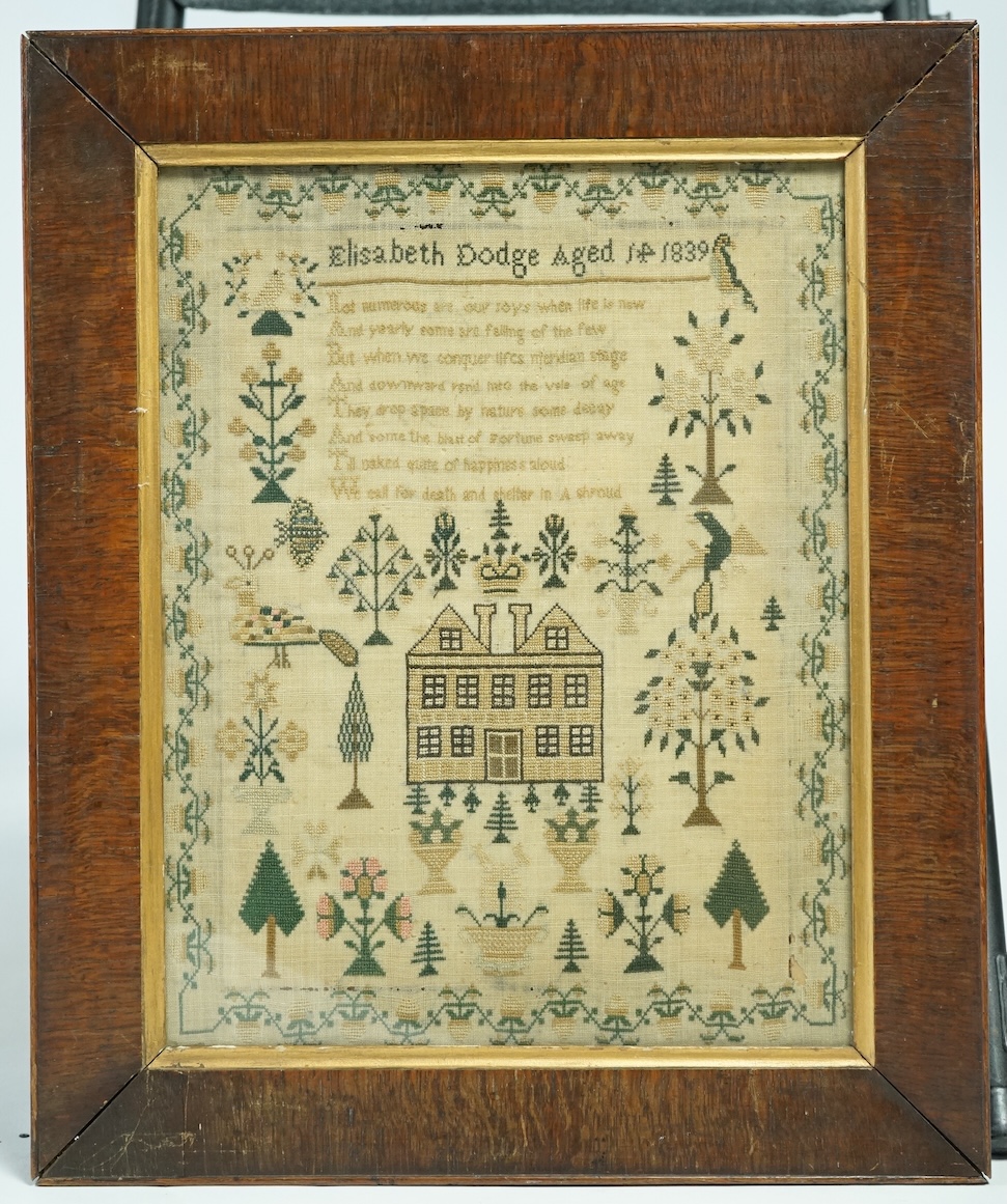Framed needlework sampler, dated 1839, by Elizabeth Dodge ages 14 years. Worked with spot motifs of a house, crown, peacock, birds, trees and flowers with floral border. 31,5cm wide x 40.5cm high. Condition - some moth h